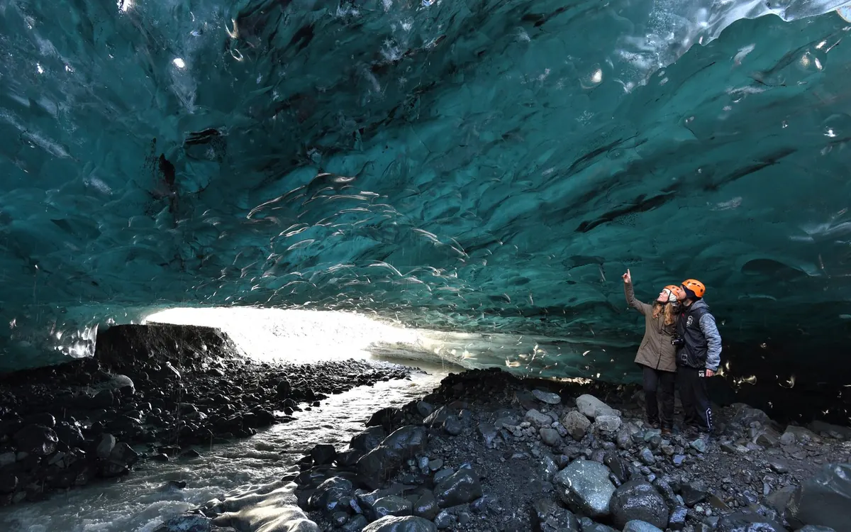 Eau de fonte s&rsquo;écoulant devant l&rsquo;entrée d&rsquo;une grotte de glace en Islande