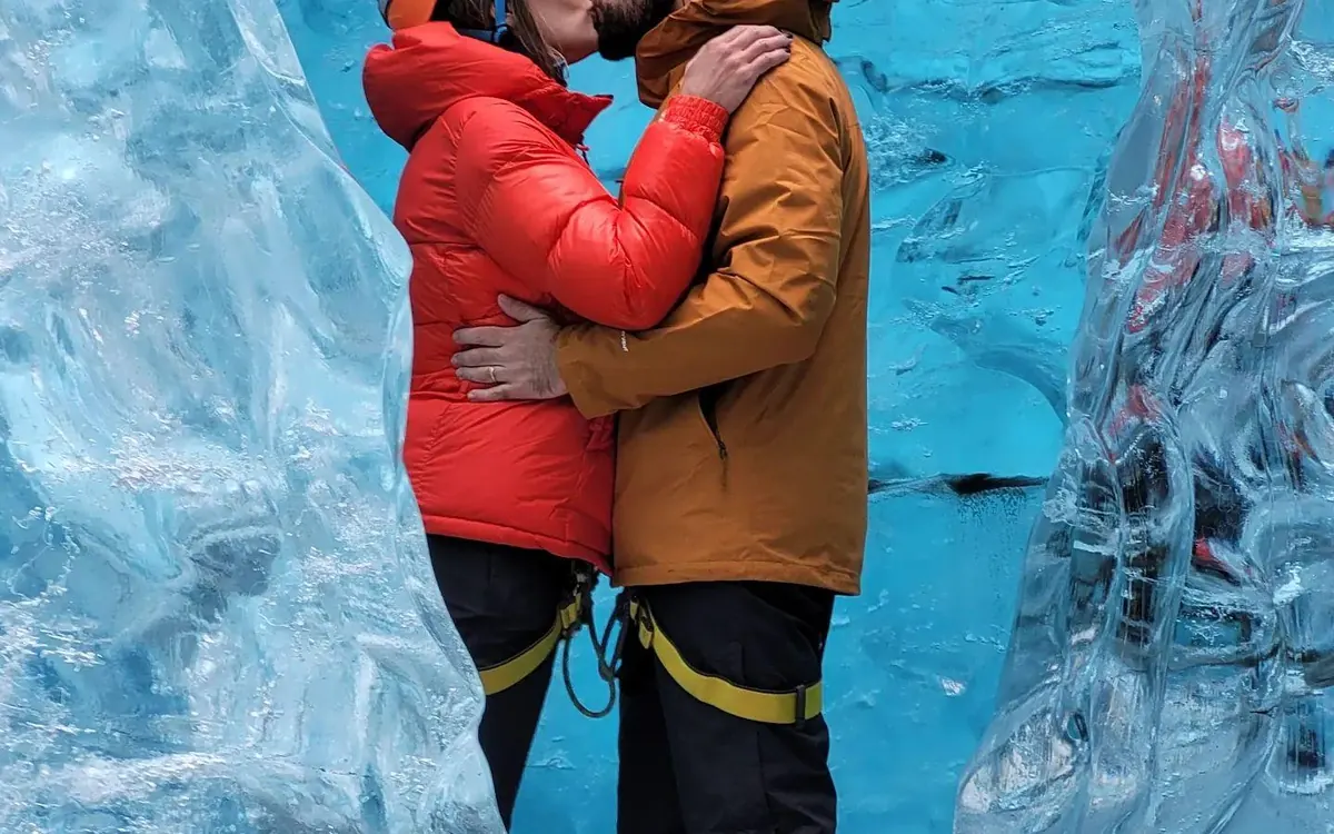 A family in warm clothing standing inside a blue ice cave in Iceland