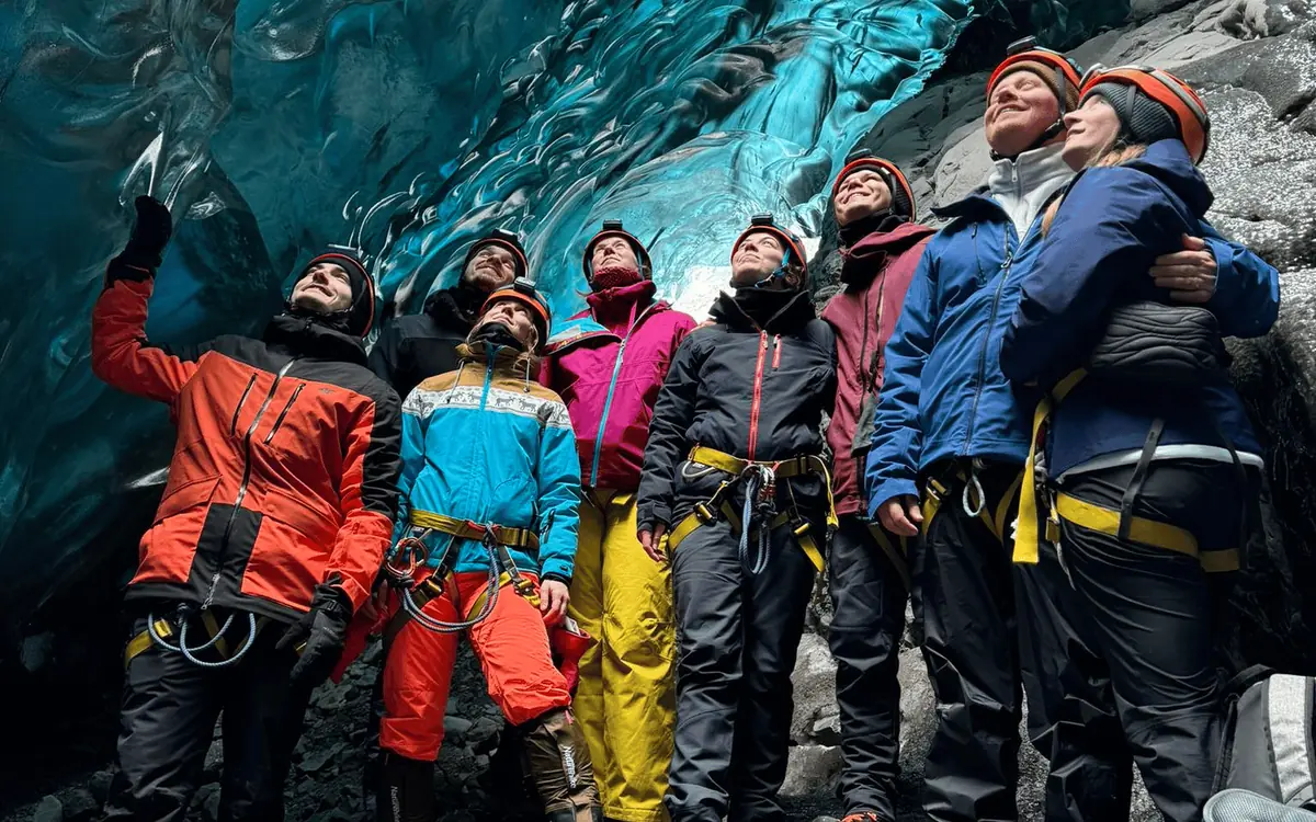 A small group looking up at the blue ceiling of an ice cave in Iceland