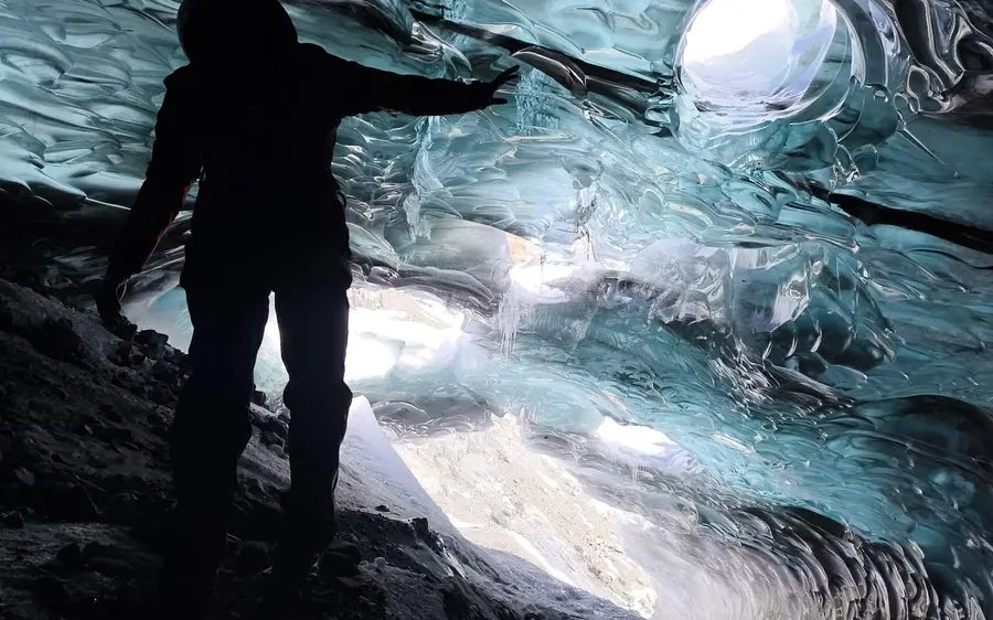 Una persona en silueta en la boca de una cueva de hielo en Breidamerkurjokull, Islandia