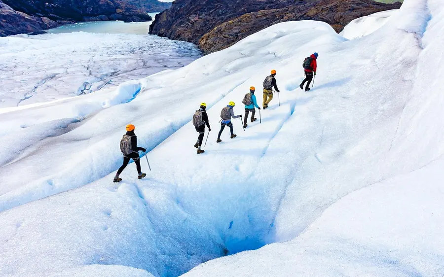 Una fila de excursionistas cruzando un glaciar blanco hacia una cueva de hielo en Islandia