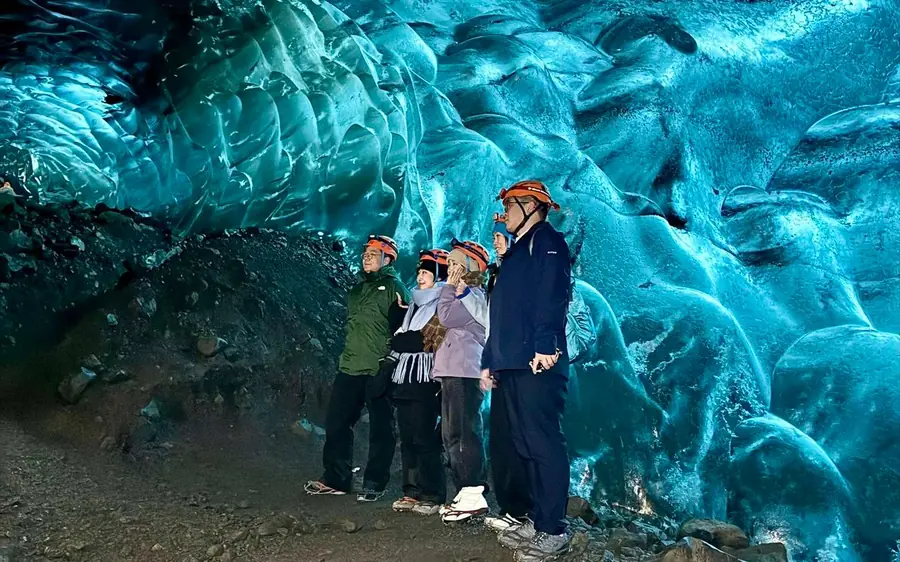Un grupo pequeño mirando hacia el techo azul de una cueva de hielo en Islandia