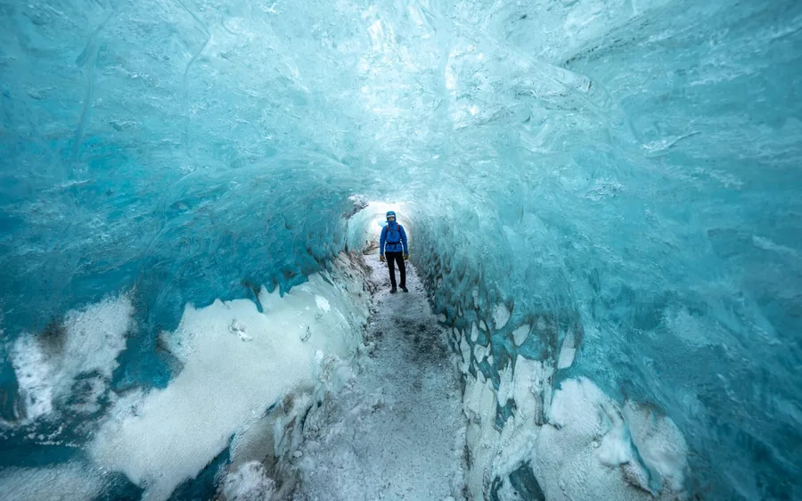 Un amplio túnel de hielo azul en el glaciar Vatnajokull con una persona al fondo