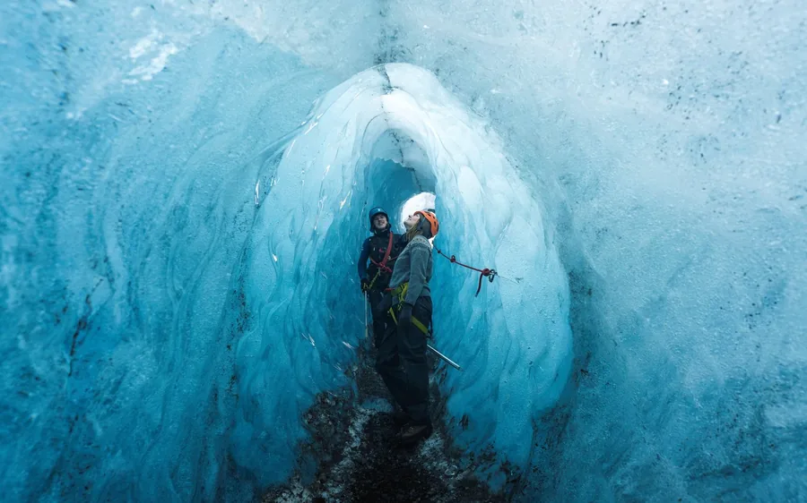 Una persona de pie dentro de un túnel de hielo azul en el glaciar Vatnajokull, Skaftafell